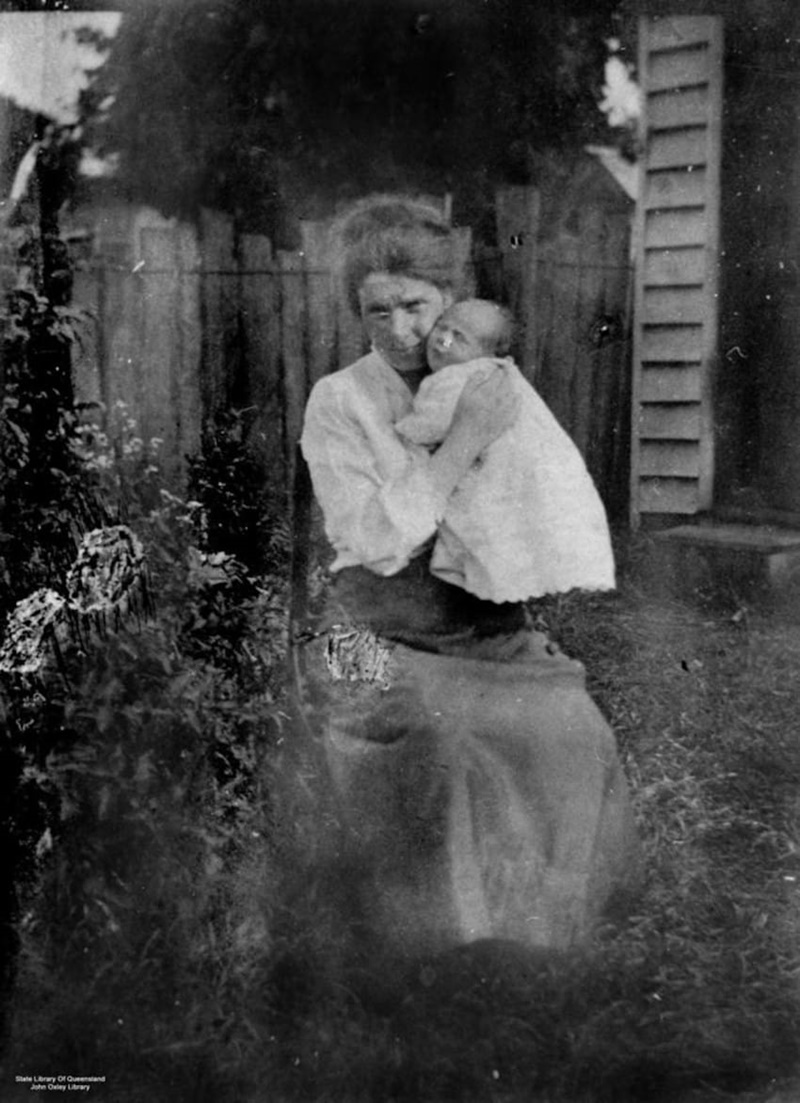 deckoStateLibQld_1_128146_Pioneer_woman_holding_a_baby_at_Toowoomba_Queensland_1920-1930-850x1172